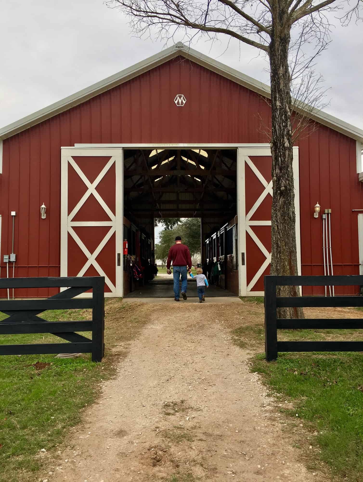 Father and son walking through horse barn