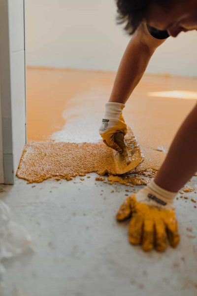 Professional construction worker applying floor paint or a new layer for a epoxy cast coating floor